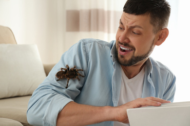 Photo of Scared man with tarantula at home. Arachnophobia (fearspiders)