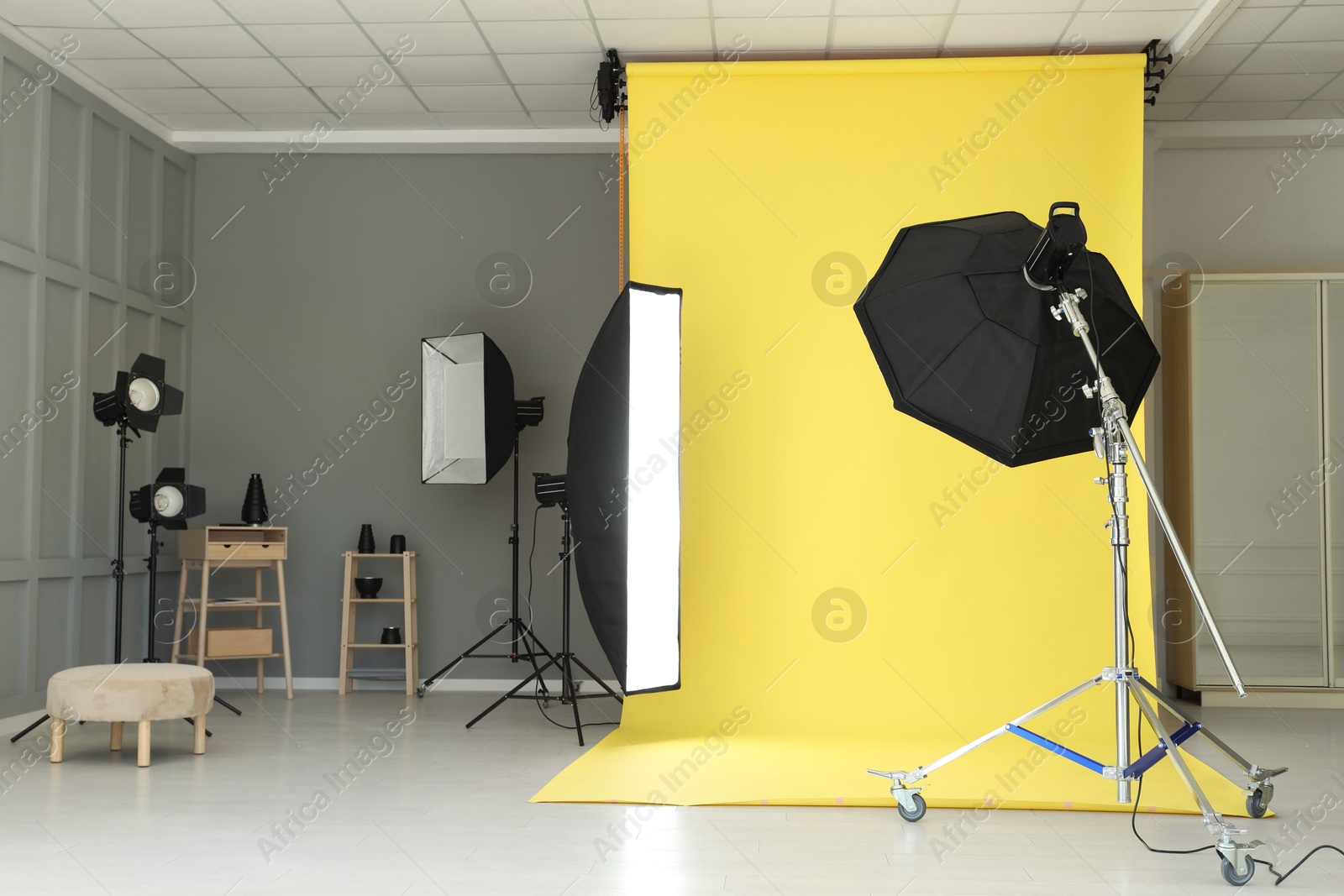 Photo of Yellow photo background and professional lighting equipment in modern studio