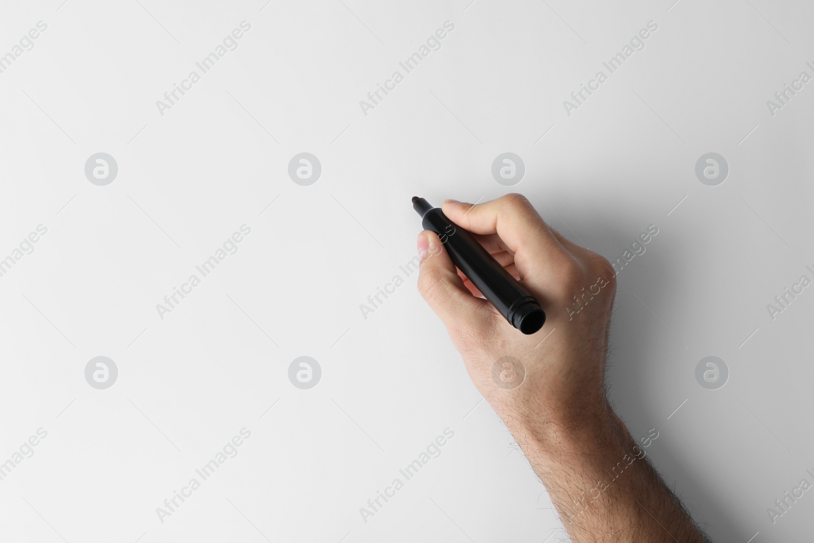 Photo of Man holding black marker on white background, top view