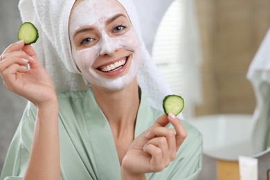 Photo of Woman with face mask and cucumber slices in bathroom, space for text. Spa treatments