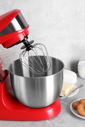 Photo of Modern red stand mixer, cookies and butter on light gray marble table