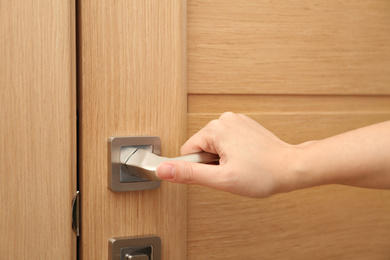 Photo of Woman opening door indoors, closeup of hand