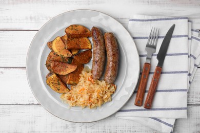 Photo of Plate with sauerkraut, sausages and potatoes on white wooden table, flat lay