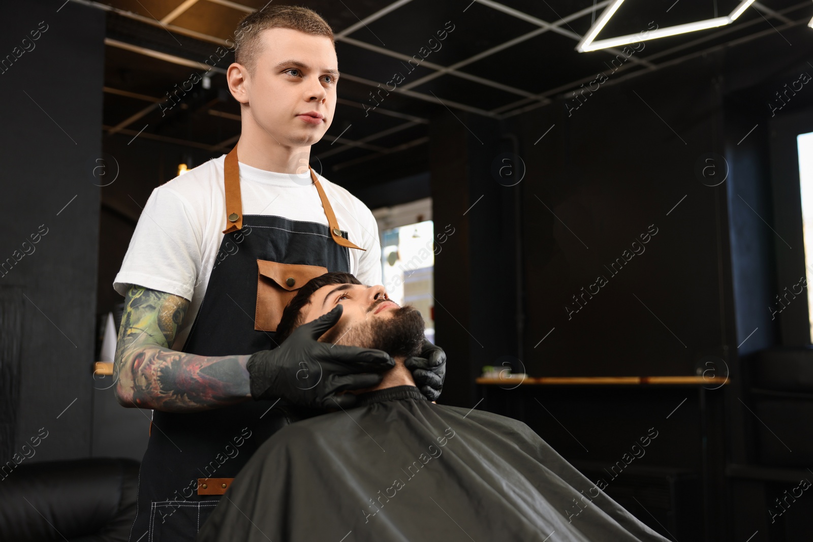 Photo of Professional hairdresser working with bearded client in barbershop