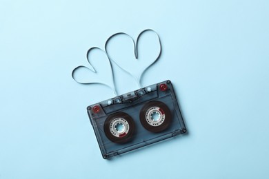 Photo of Music cassette and hearts made with tape on light blue background, top view. Listening love song