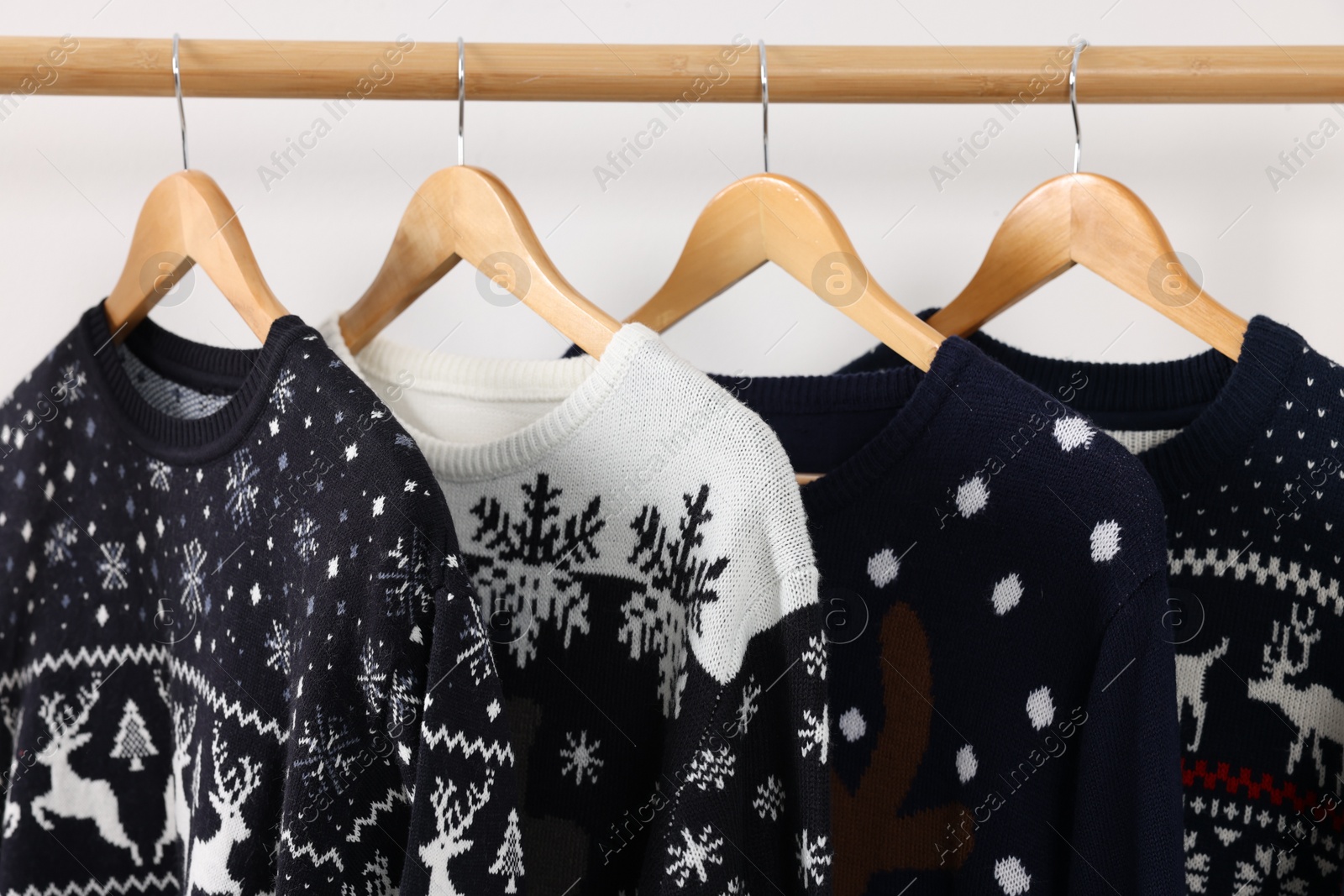 Photo of Rack with different Christmas sweaters on white background, closeup