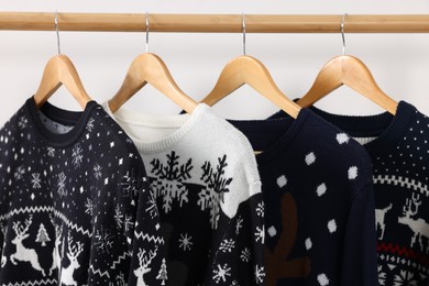 Rack with different Christmas sweaters on white background, closeup