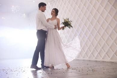 Happy newlywed couple dancing together in festive hall