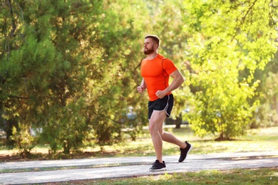 Young man running in park on sunny day