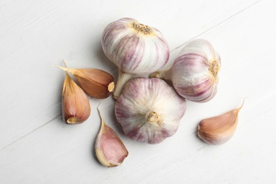 Photo of Fresh organic garlic on white wooden table, flat lay