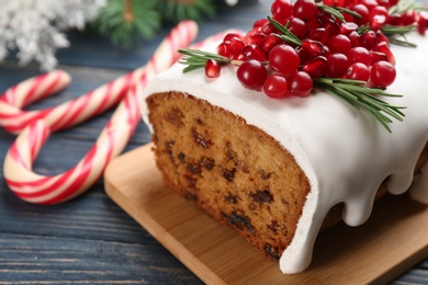 Photo of Traditional classic Christmas cake decorated with cranberries, pomegranate seeds and rosemary on wooden table, closeup