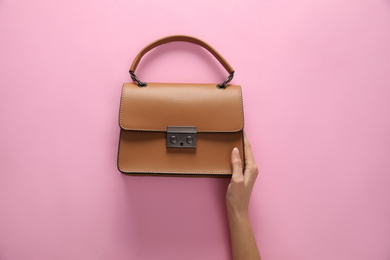 Woman holding stylish handbag on pink background, closeup