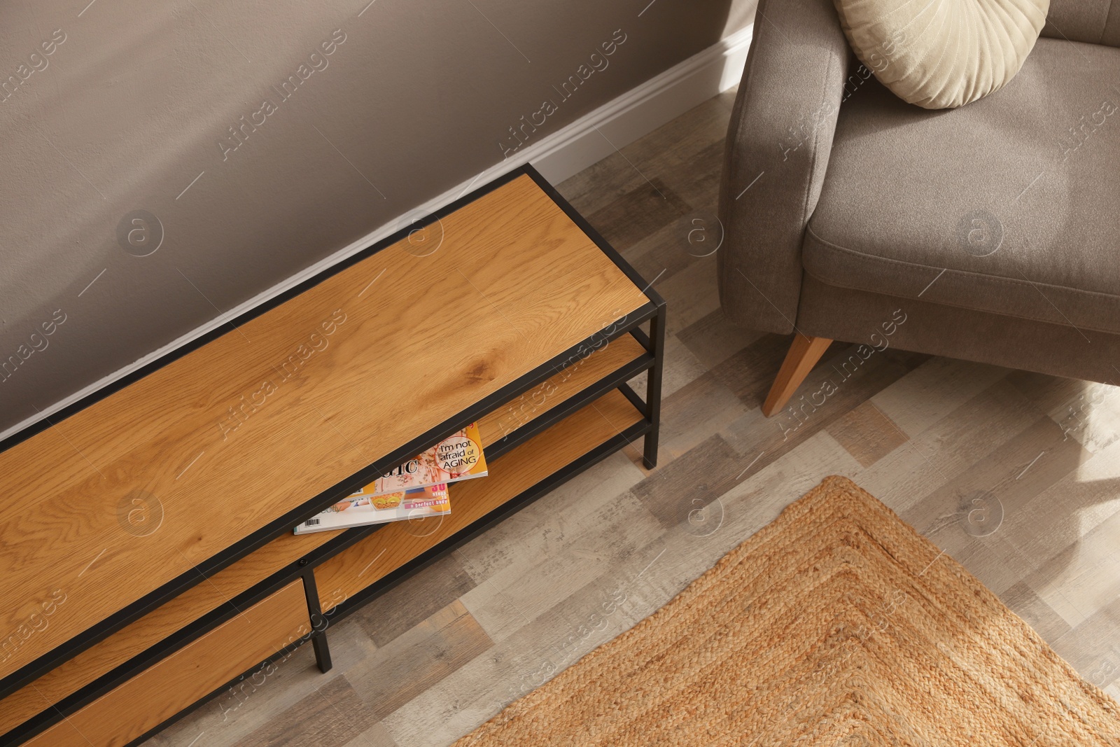 Photo of Wooden cabinet and comfortable armchair near grey wall in room, above view