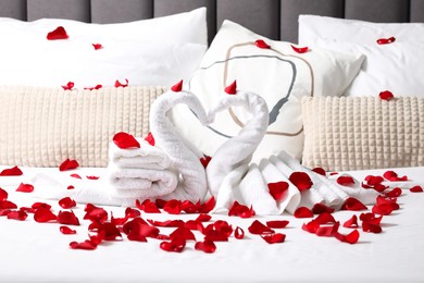 Honeymoon. Swans made with towels and beautiful rose petals on bed