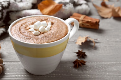 Cup of hot drink on grey wooden table, closeup. Cozy autumn atmosphere