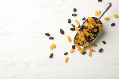 Scoop of raisins on wooden background, top view with space for text. Dried fruit as healthy snack