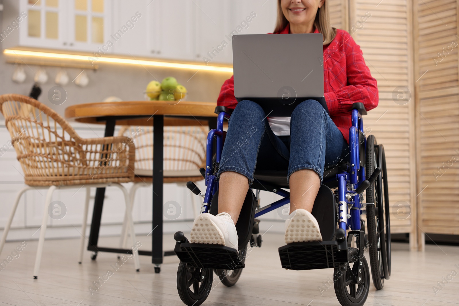 Photo of Woman in wheelchair using laptop at home, closeup