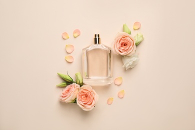 Photo of Flat lay composition with bottle of perfume and fresh flowers on beige background