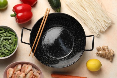 Photo of Black wok, chopsticks and products on color table, flat lay