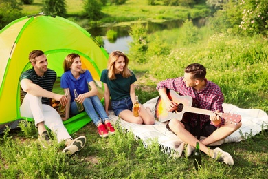Photo of Group of young people resting in wilderness. Camping season