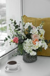 Photo of Bouquet of beautiful flowers and coffee on windowsill