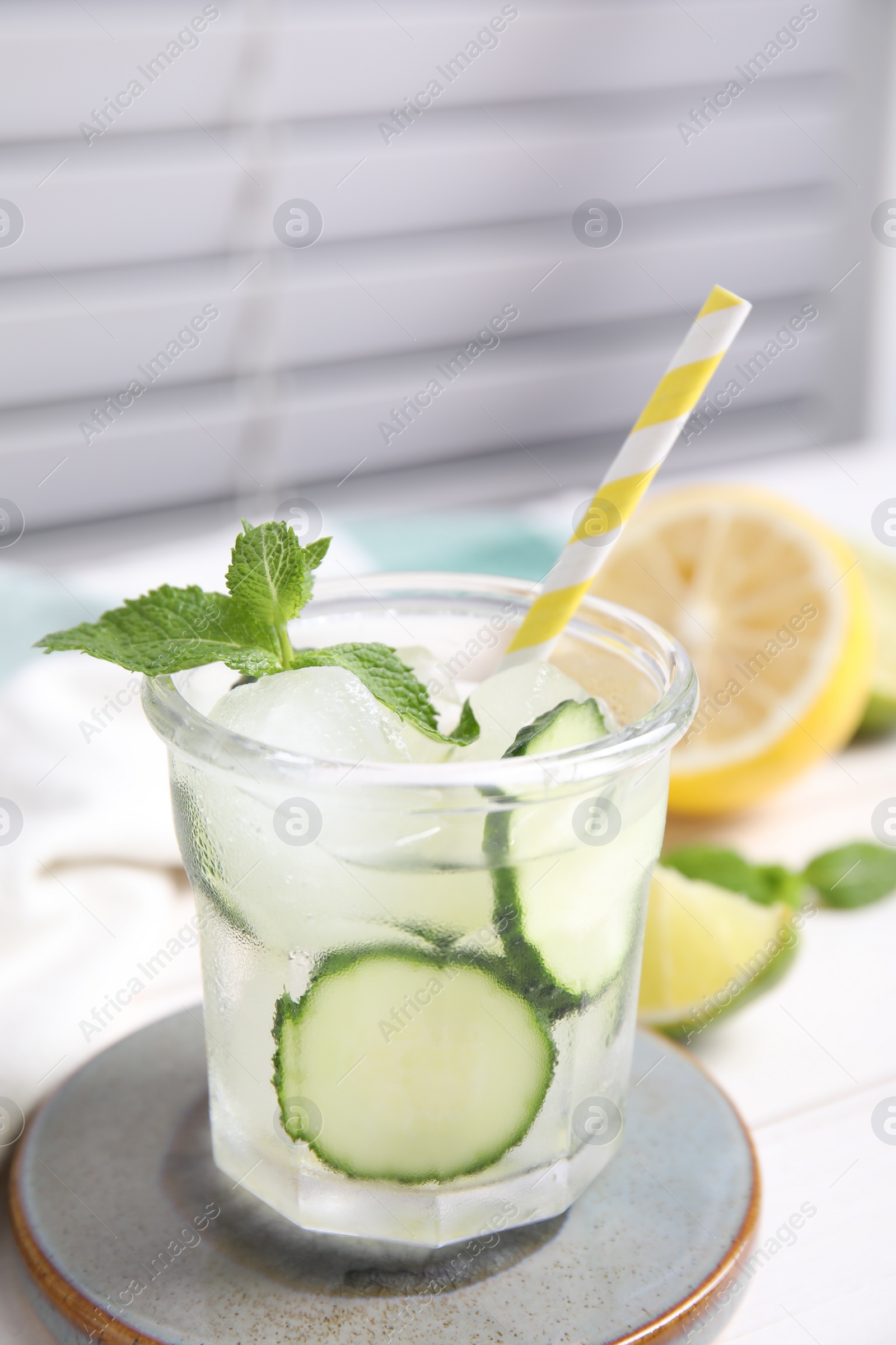 Photo of Glass of refreshing cucumber water with mint on white wooden table, closeup