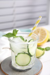 Glass of refreshing cucumber water with mint on white wooden table, closeup