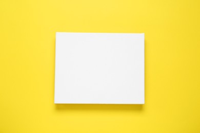 Photo of Blank canvas on yellow background, top view. Space for design