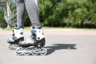 Photo of Woman with modern inline roller skates in city park, closeup