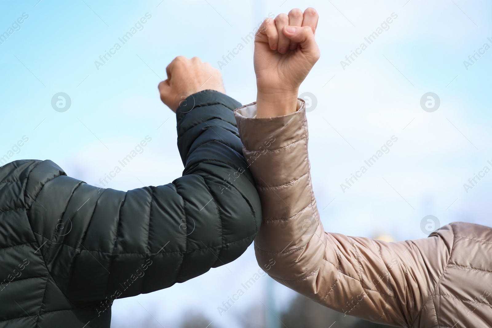 Photo of People greeting each other by bumping elbows instead of handshake outdoors, closeup