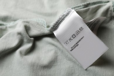 Photo of Clothing label on pale olive garment, closeup