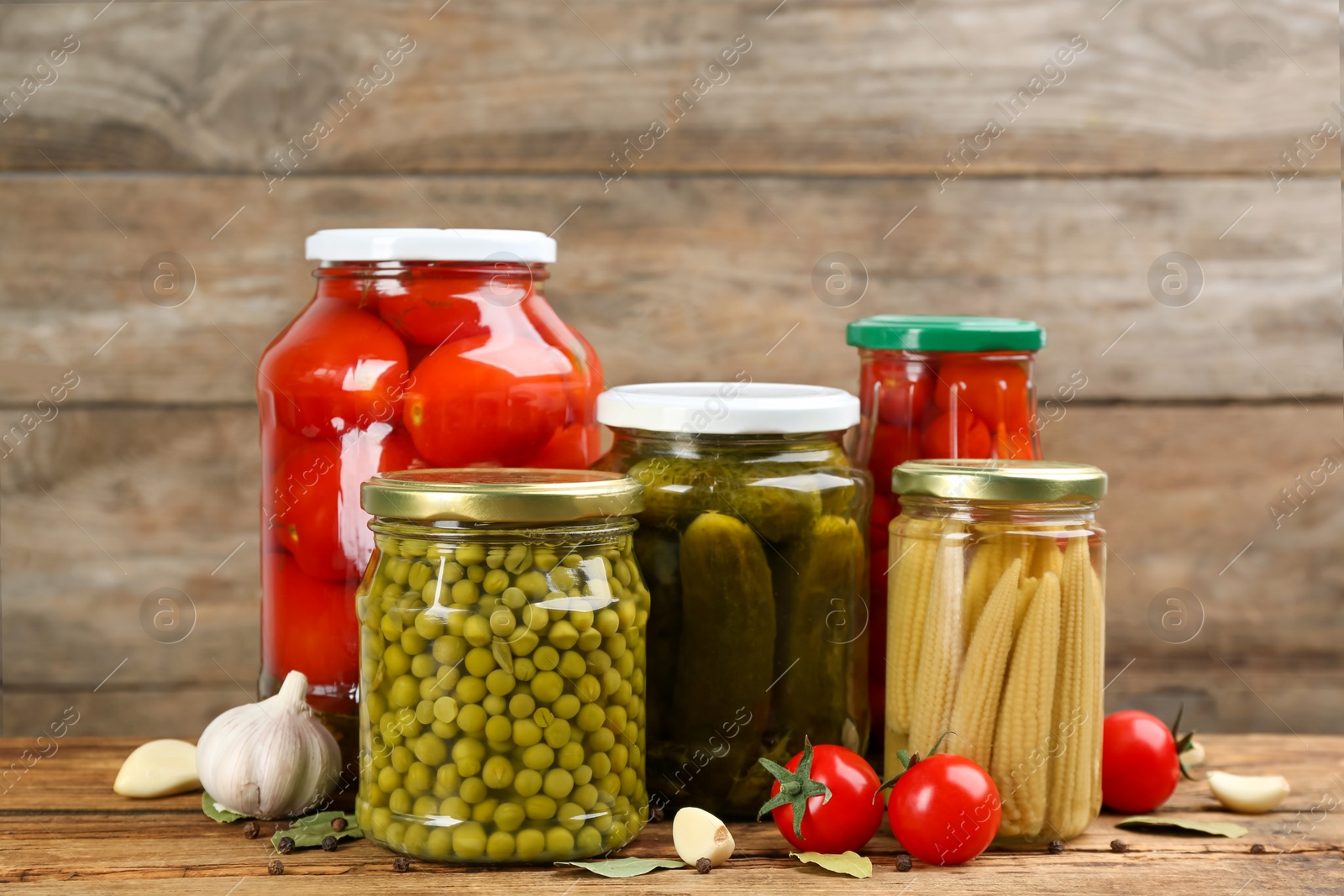 Photo of Jars of pickled vegetables on wooden table