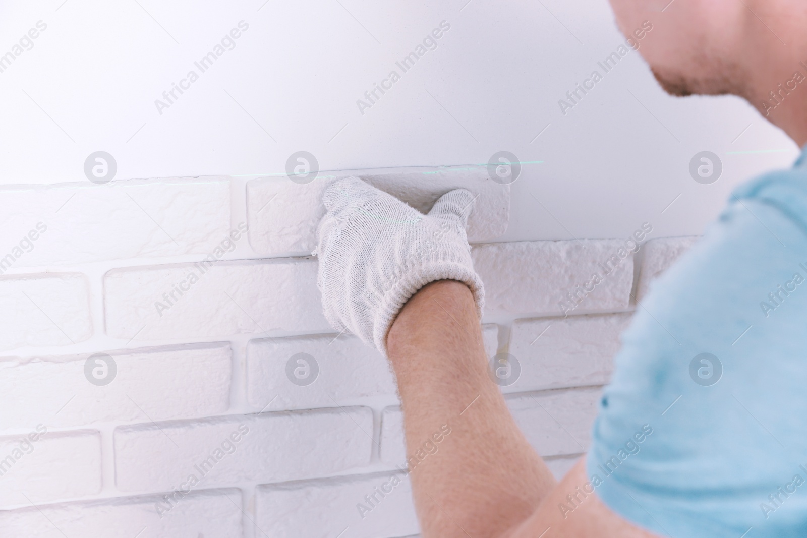 Photo of Worker installing decorative wall tiles in room, closeup