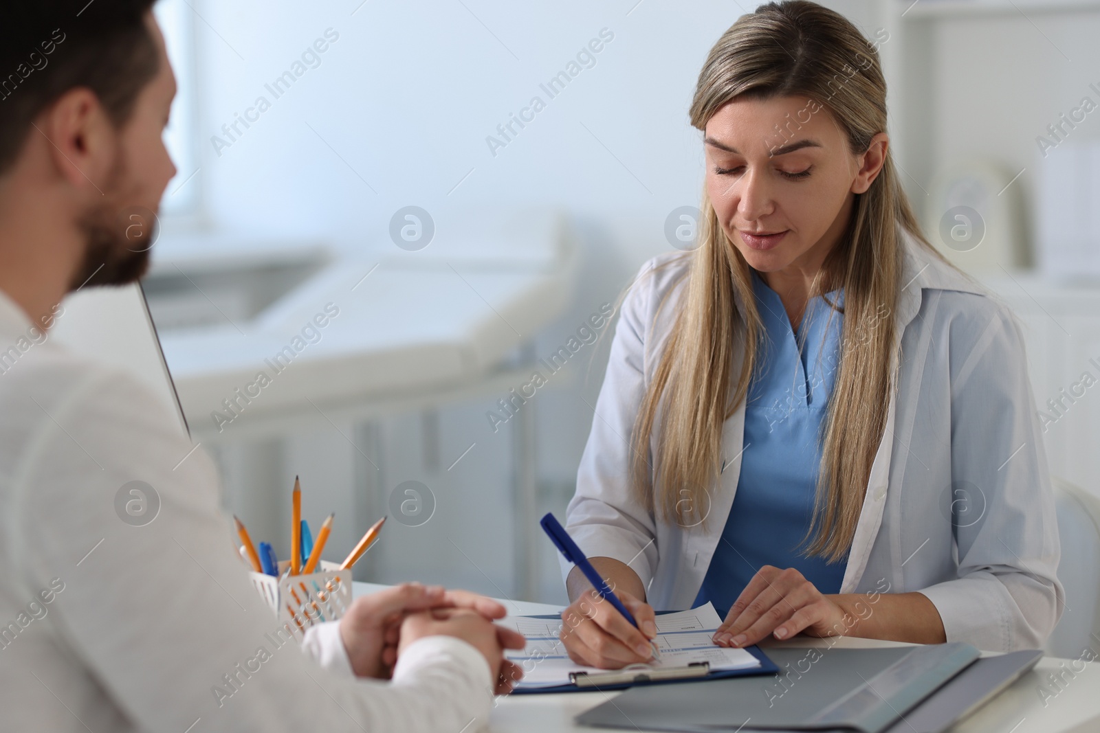 Photo of Professional doctor working with patient at white table in hospital