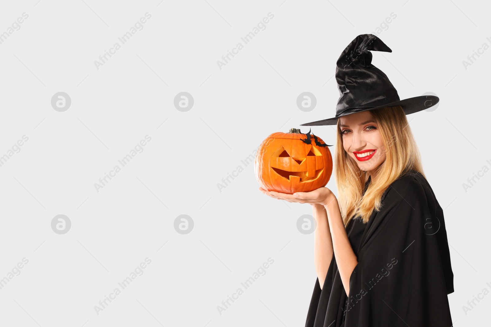 Photo of Beautiful woman in witch costume with jack o'lantern on white background, space for text. Halloween party