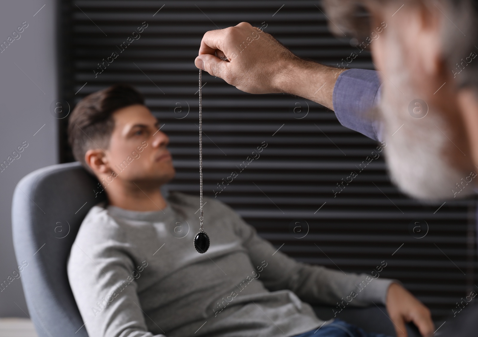 Photo of Psychotherapist using pendulum during hypnotherapy   session in office