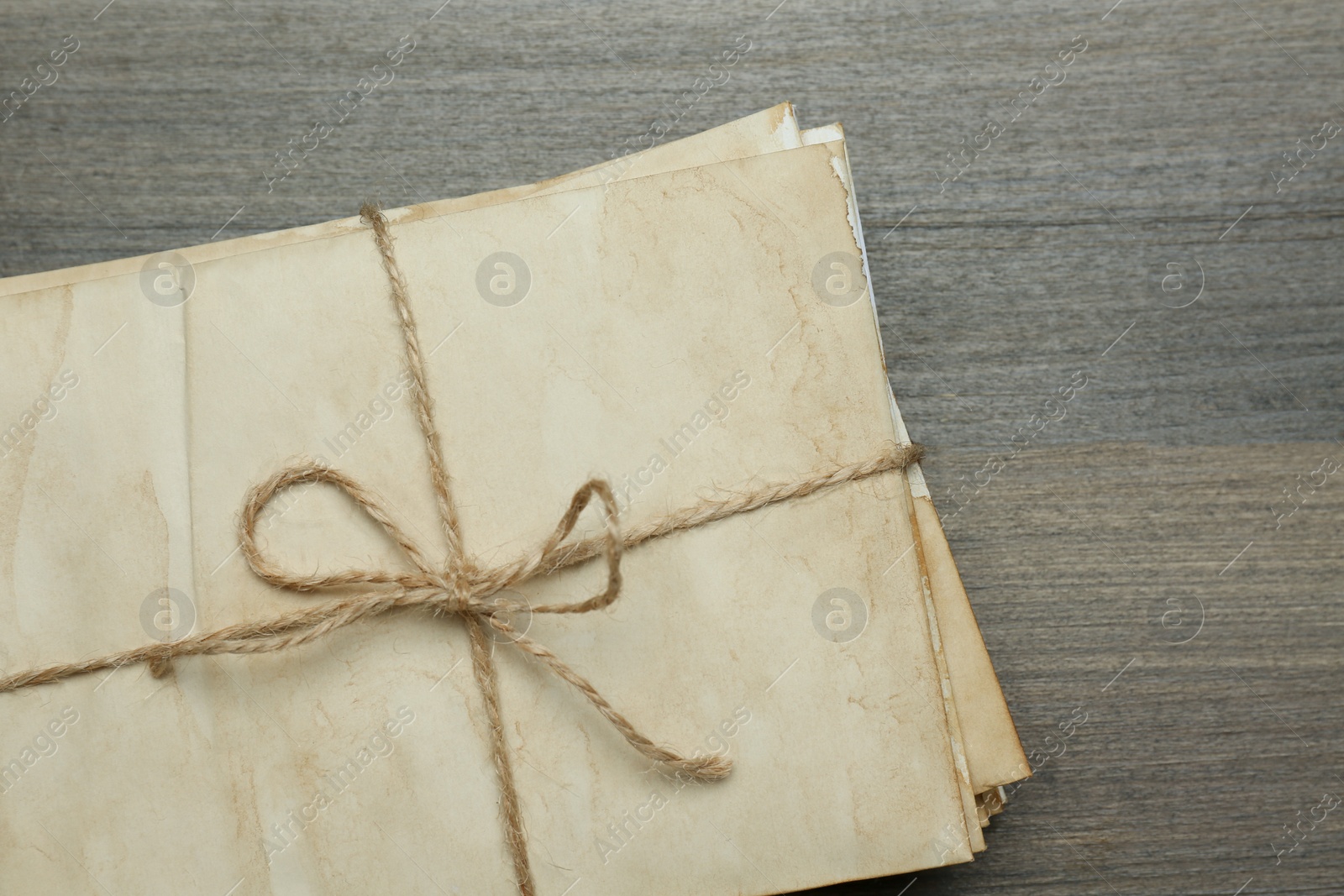 Photo of Stack of old letters tied with twine on wooden table, top view