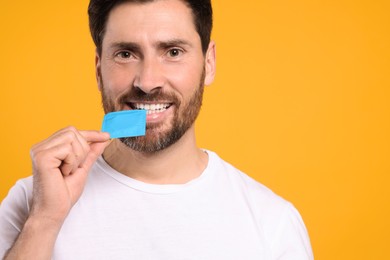 Happy man holding condom on yellow background, space for text. Safe sex