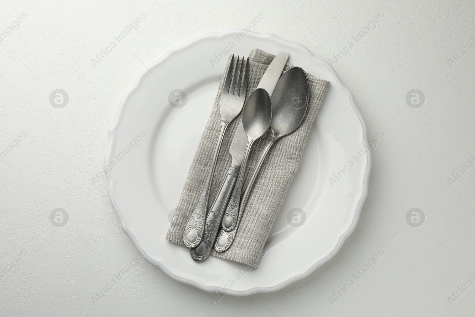 Photo of Stylish setting with cutlery and plate on white textured table, top view