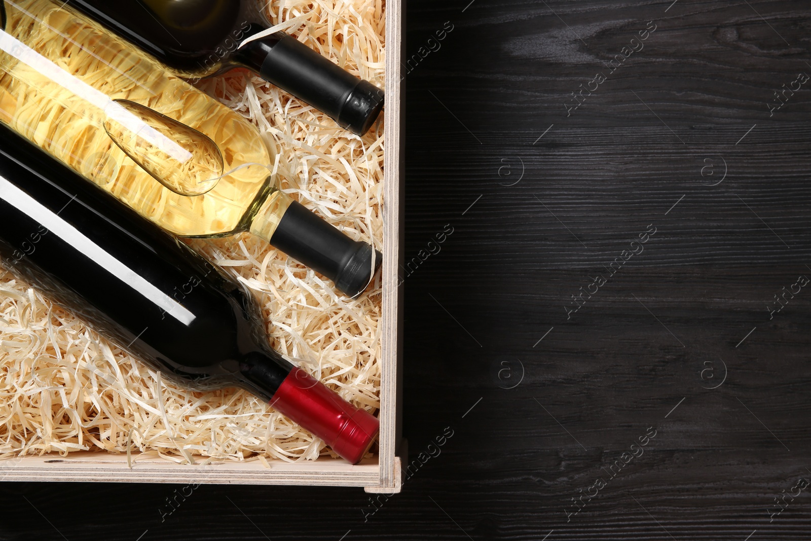 Photo of Wooden crate with bottles of wine on grey table, top view. Space for text