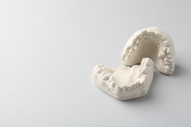 Photo of Dental model with gums on light grey background, space for text. Cast of teeth