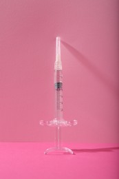 Photo of Cosmetology. One medical syringe on pink background
