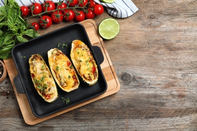 Photo of Baked stuffed zucchinis with ingredients on wooden background, flat lay. Space for text