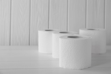 Photo of Many soft toilet paper rolls on white wooden table. Space for text