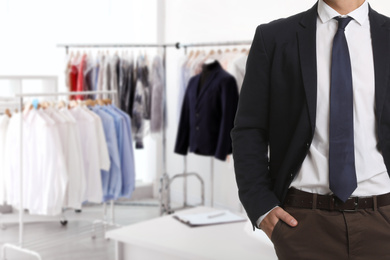 Businessman and blurred view of dry-cleaner's interior, closeup. Space for text 