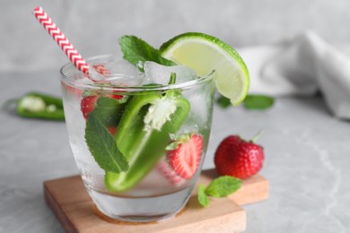 Photo of Spicy cocktail with jalapeno, strawberry, lime and mint on light grey table