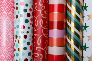 Photo of Different colorful wrapping paper rolls as background, top view