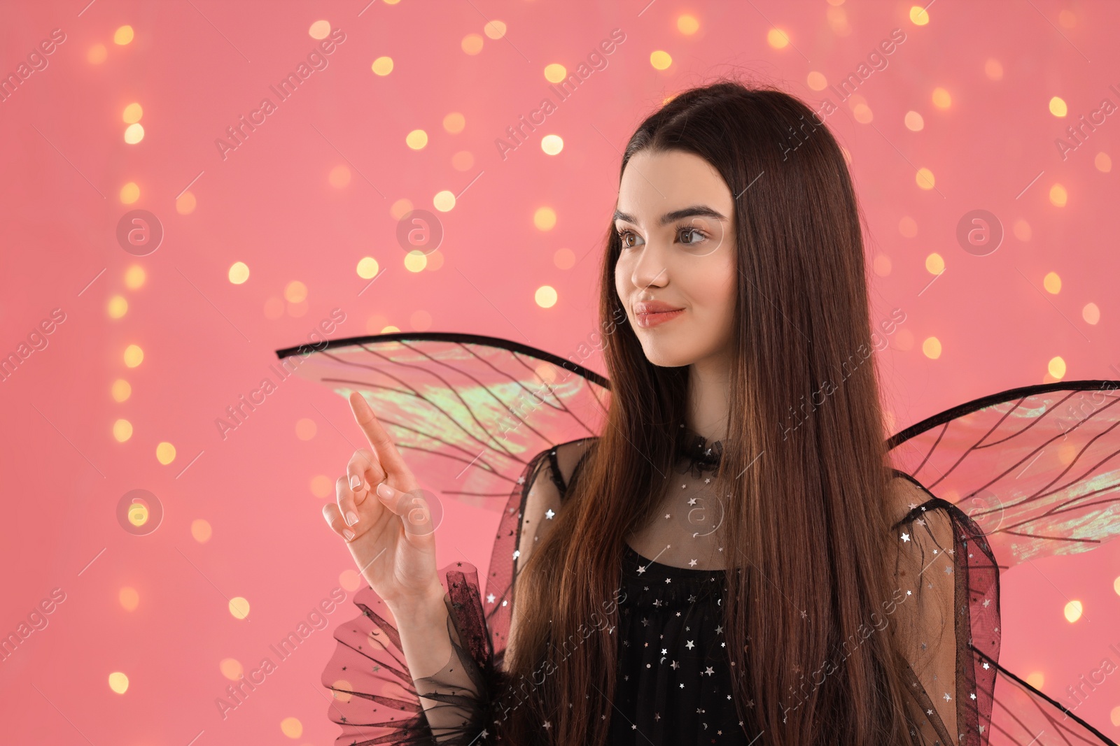 Photo of Beautiful girl in fairy costume with wings on pink background