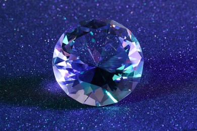 Photo of Beautiful dazzling diamond on blue glitter background