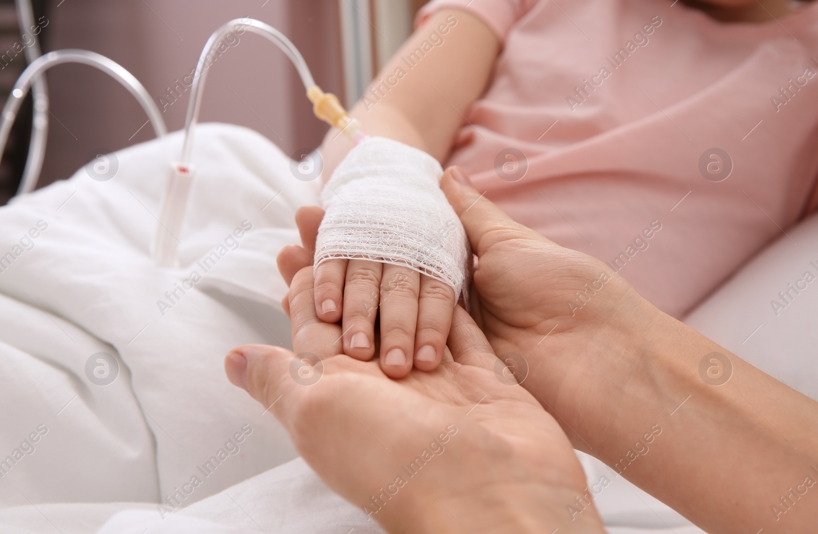 Photo of Doctor holding little child's hand with intravenous drip in hospital, closeup